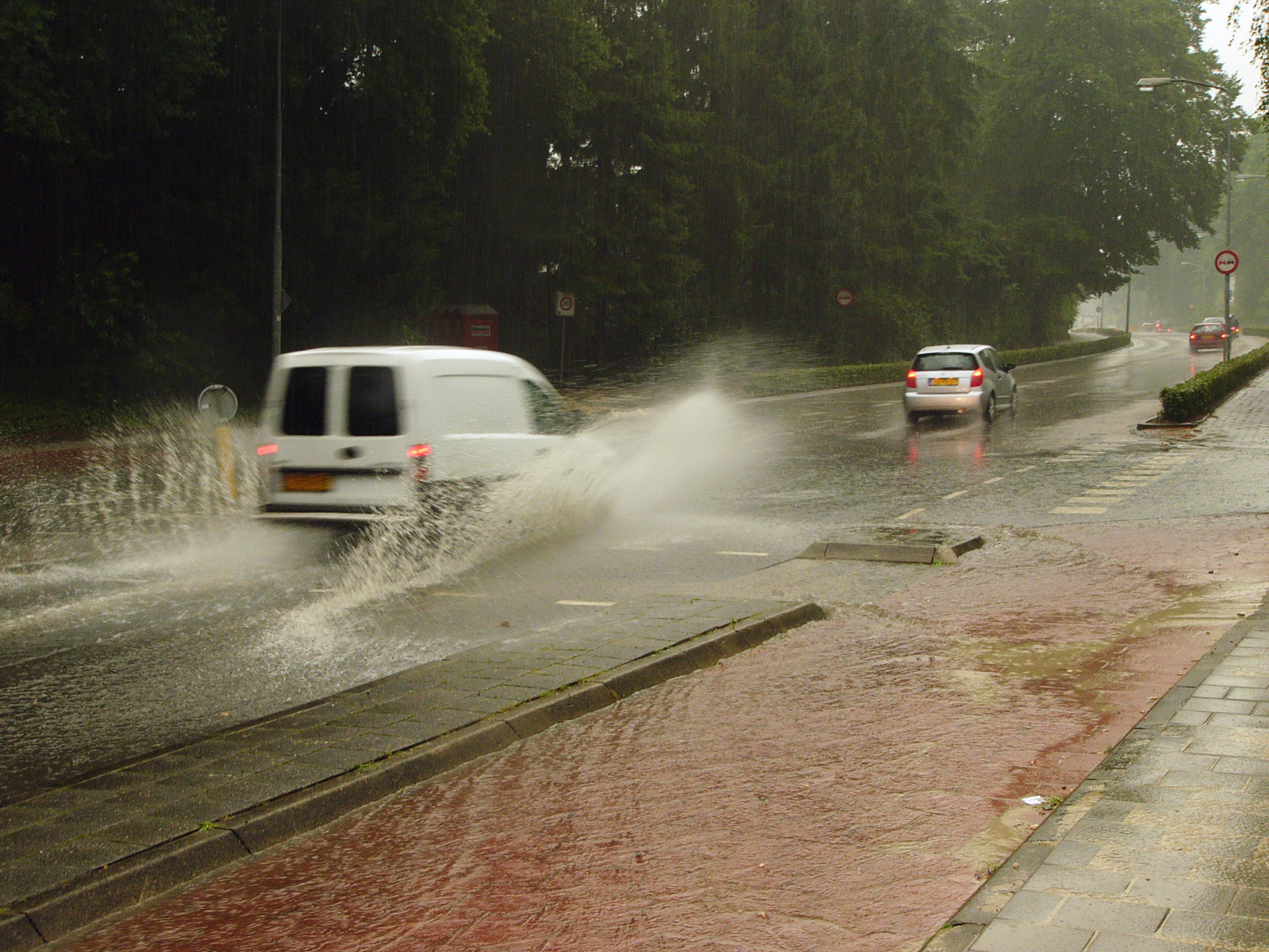 Auto rijd door weg vol met water heen